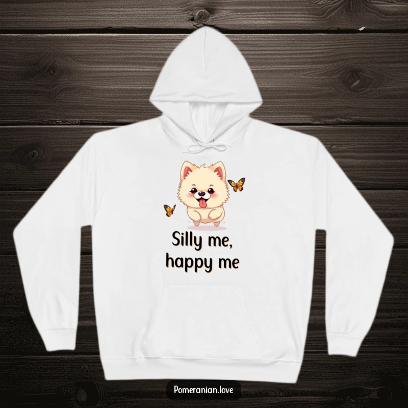 Funny Pomeranian hoodie, a silly dog with its tongue sticking out, happily chasing a butterfly, full of playful energy.